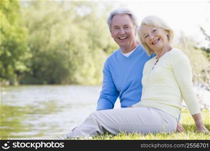 Couple outdoors at park by lake smiling
