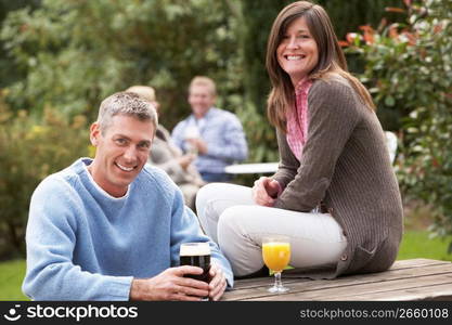 Couple Outdoors Enjoying Drink In Pub Garden