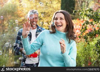 Couple Outdoors In Autumn Landscape With Bubble Machine