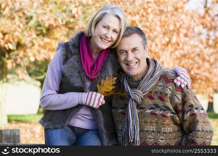 Couple outdoors in park by fence smiling (selective focus)