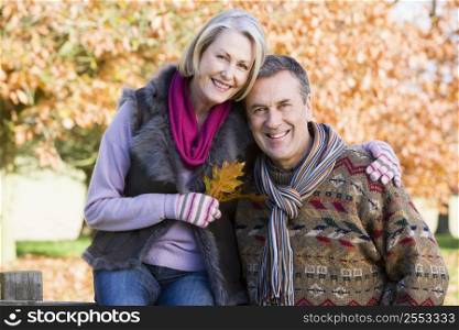Couple outdoors in park by fence smiling (selective focus)