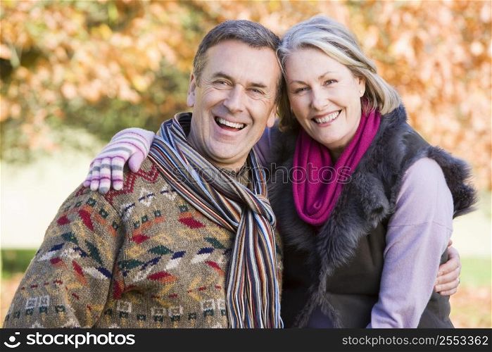 Couple outdoors in park embracing and smiling (selective focus)