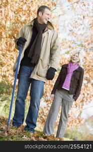 Couple outdoors raking leaves and smiling (selective focus)