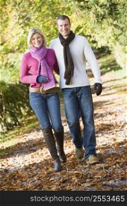 Couple outdoors walking on path in park smiling (selective focus)