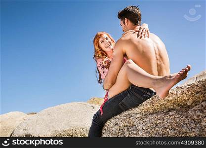 Couple outdoors, woman sitting on man&acute;s lap, face to face