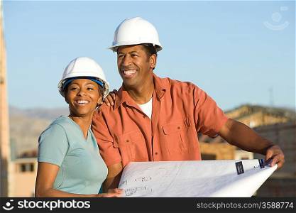 Couple over blueprint in construction site