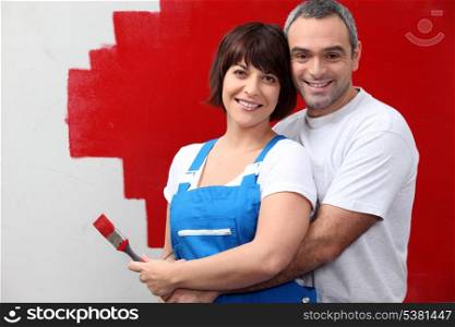 couple painting a wall in red