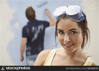 Couple painting wall, woman in foreground