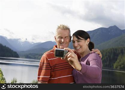 Couple photographing selves, mountains in background