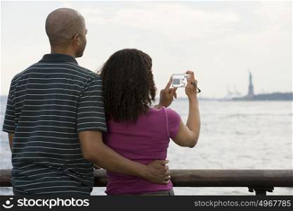 Couple photographing statue of liberty