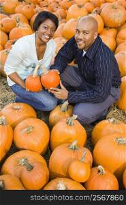 Couple picking out pumpkins and smiling at outdoor market.