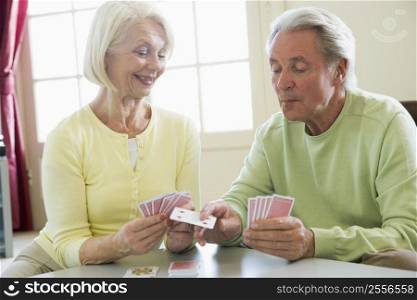Couple playing cards in living room smiling