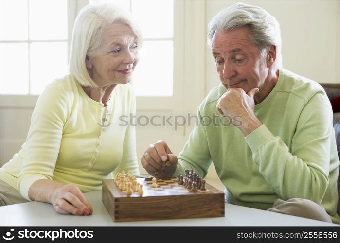 Couple playing chess in living room smiling