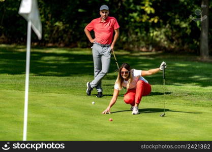 Couple playing golf, young woman reading green, getting ready to putt