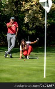 Couple playing golf, young woman reading green, getting ready to putt