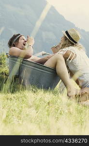 Couple playing in metal tub outdoors