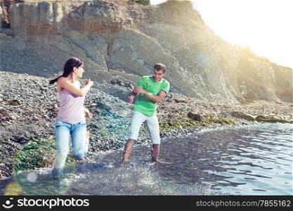 Couple playing in water on the beach, splashes, sunbeams and lens flares, motion blur