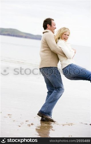 Couple playing on beach smiling