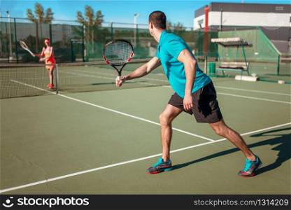 Couple playing tennis on outdoor court. Summer season active sport game. Couple playing tennis on outdoor court