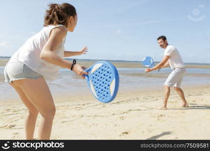 couple playing with bat and ball on the beach