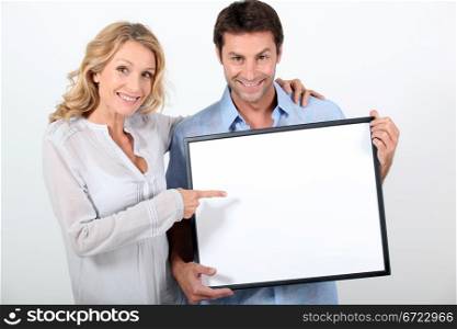 Couple pointing at blank board