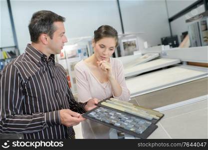 couple pointing at ceramic tile for bathroom floor in store