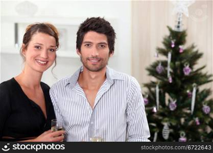 Couple posing in front of their Christmas tree
