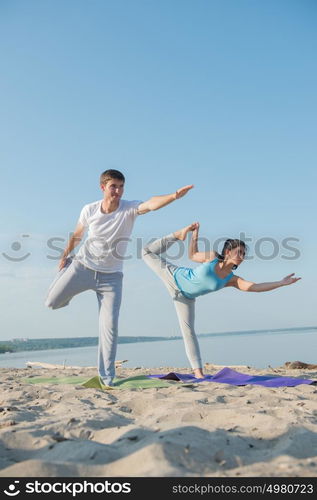 Couple practicing yoga at the beach