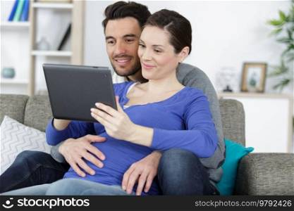 couple pregnant woman and husband looking tablet