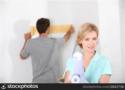 Couple preparing to wallpaper a white room