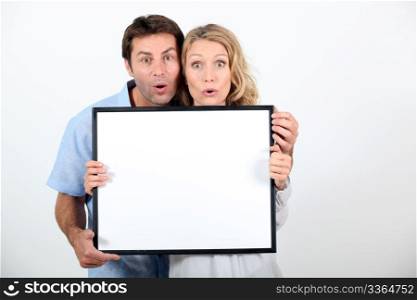 Couple pulling a funny face and holding a blank board ready for your text