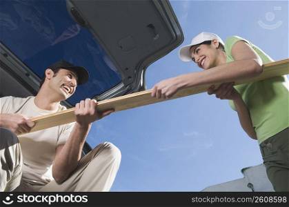 Couple pulling a wooden plank from each other