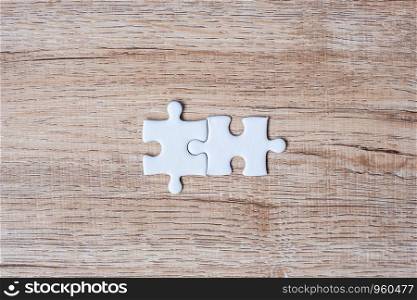 Couple puzzle pieces on wood table background. Business solutions, mission target, successful, goals, cooperation, partnership and strategy concept