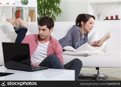 Couple reading a book and a laptop