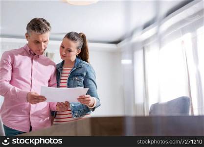 Couple reading agreement paper while standing in apartment