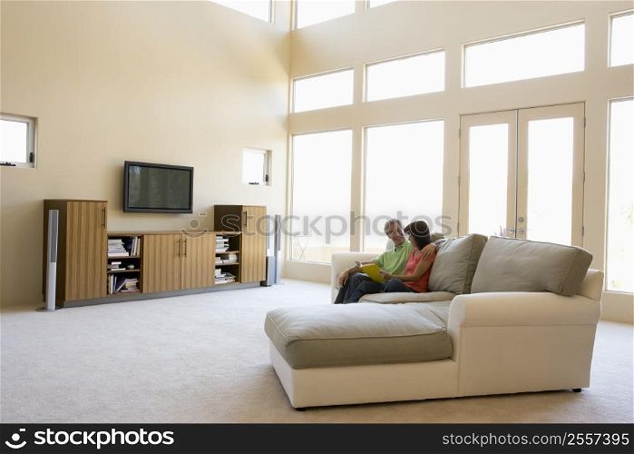 Couple reading book in living room smiling