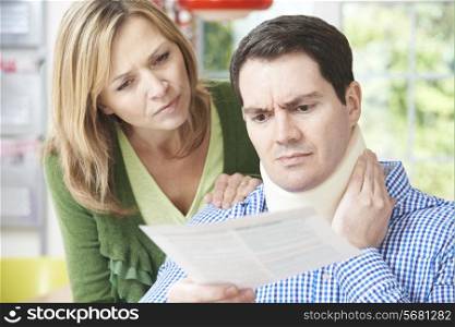 Couple Reading Letter In Respect Of Husband&rsquo;s Neck Injury