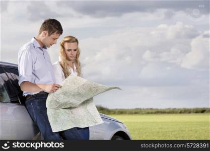 Couple reading map while leaning on car at countryside