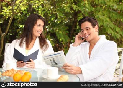 Couple reading over an outdoor breakfast
