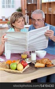 Couple reading the newspaper over breakfast