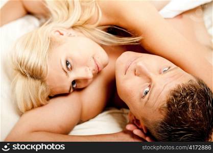 Couple relaxing after the act of sex and looking at camera