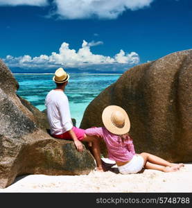 Couple relaxing among granite rocks on a tropical beach Anse Source d&rsquo;Argent at Seychelles, La Digue.