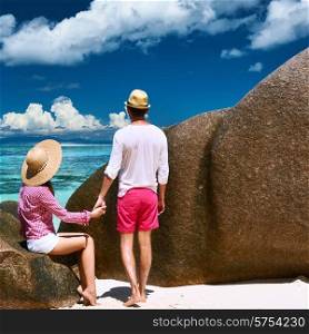 Couple relaxing among granite rocks on a tropical beach Anse Source d&rsquo;Argent at Seychelles, La Digue.