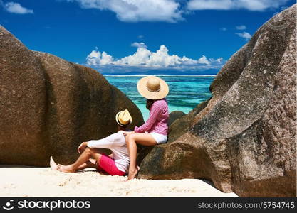 Couple relaxing among granite rocks on a tropical beach Anse Source d&rsquo;Argent at Seychelles, La Digue.