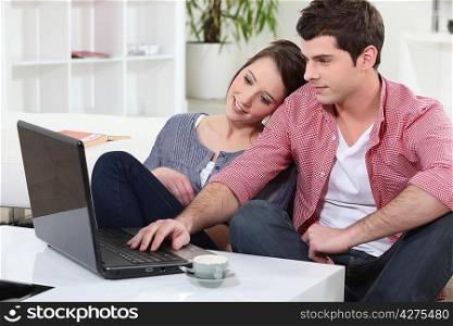 Couple relaxing at home in front of their laptop