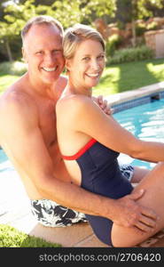 Couple Relaxing By Pool In Garden