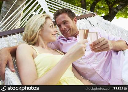 Couple Relaxing In Beach Hammock Drinking Champagne