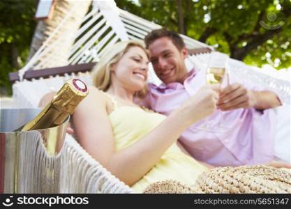 Couple Relaxing In Beach Hammock Drinking Champagne