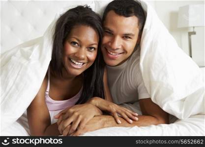 Couple Relaxing In Bed Hiding Under Duvet