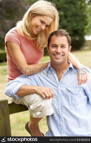 Couple Relaxing In Countryside Sitting On Fence